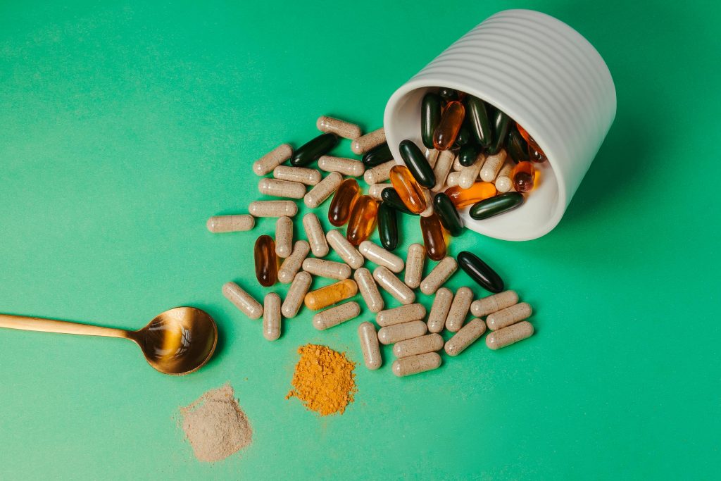 pexels-photo-17820709-17820709 A mix of capsules, pills, and powder on green background with spoon.